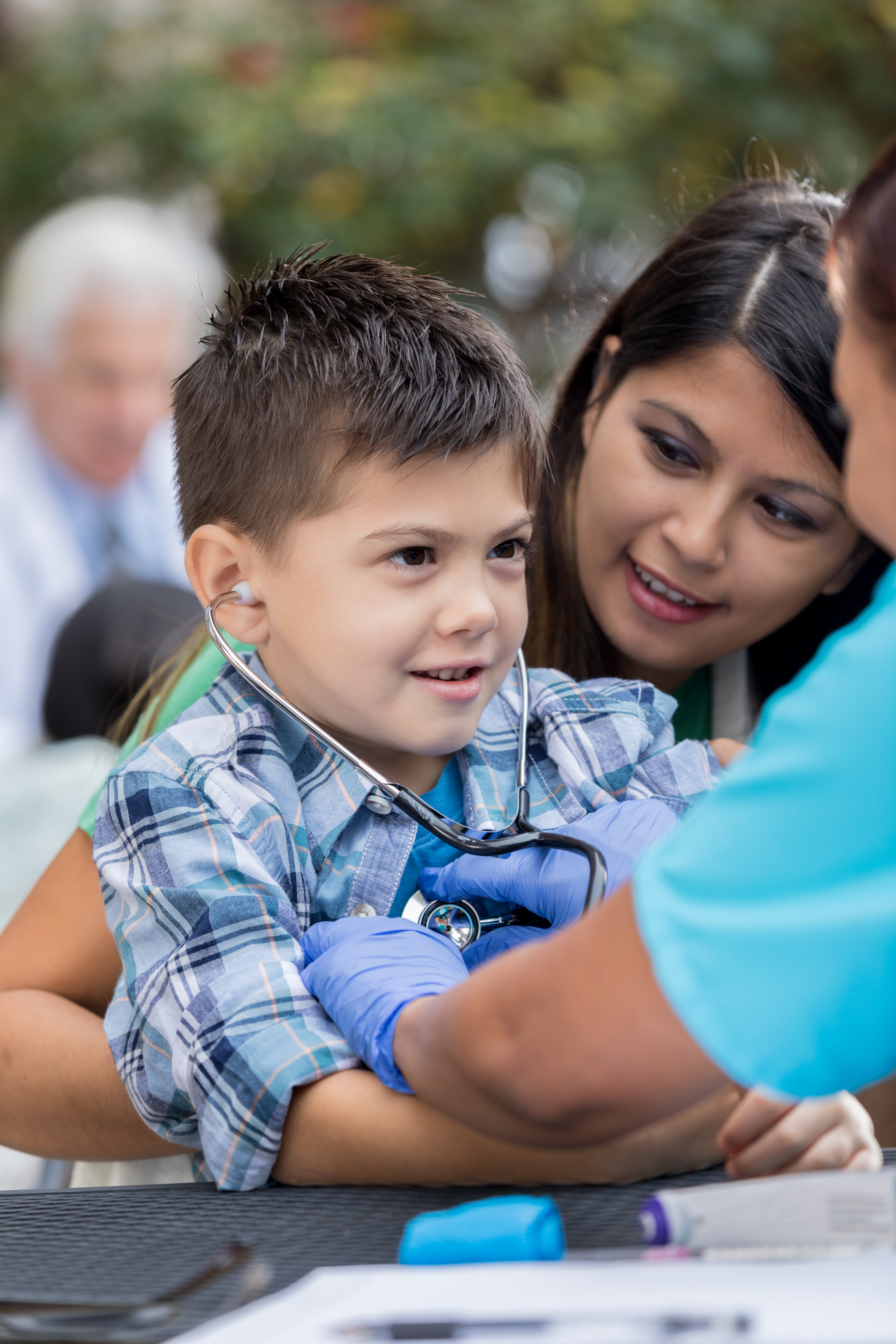 Young boy being examined with a stethoscope at a community health event.
