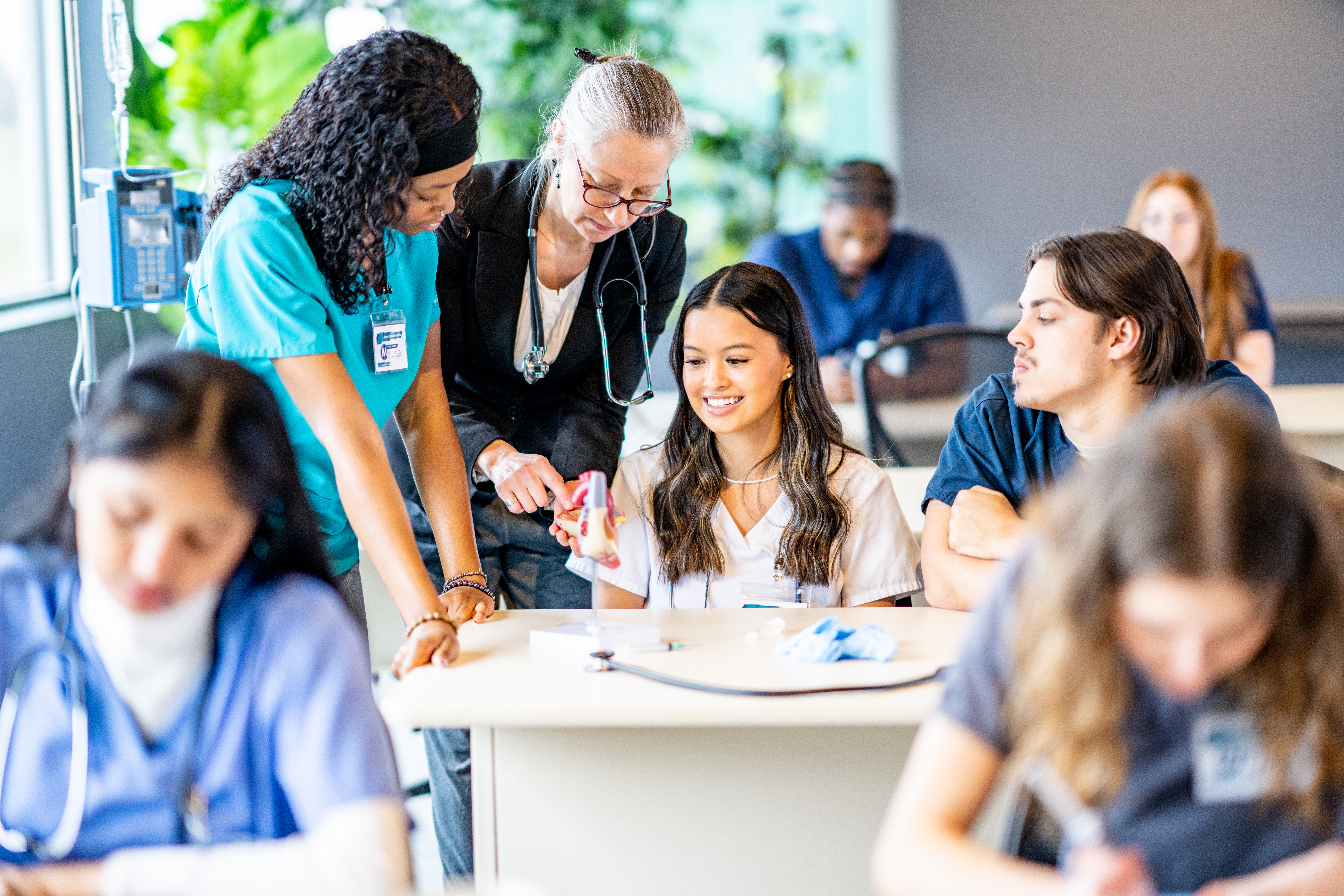 Nursing instructor guiding students during a hands-on clinical training class.