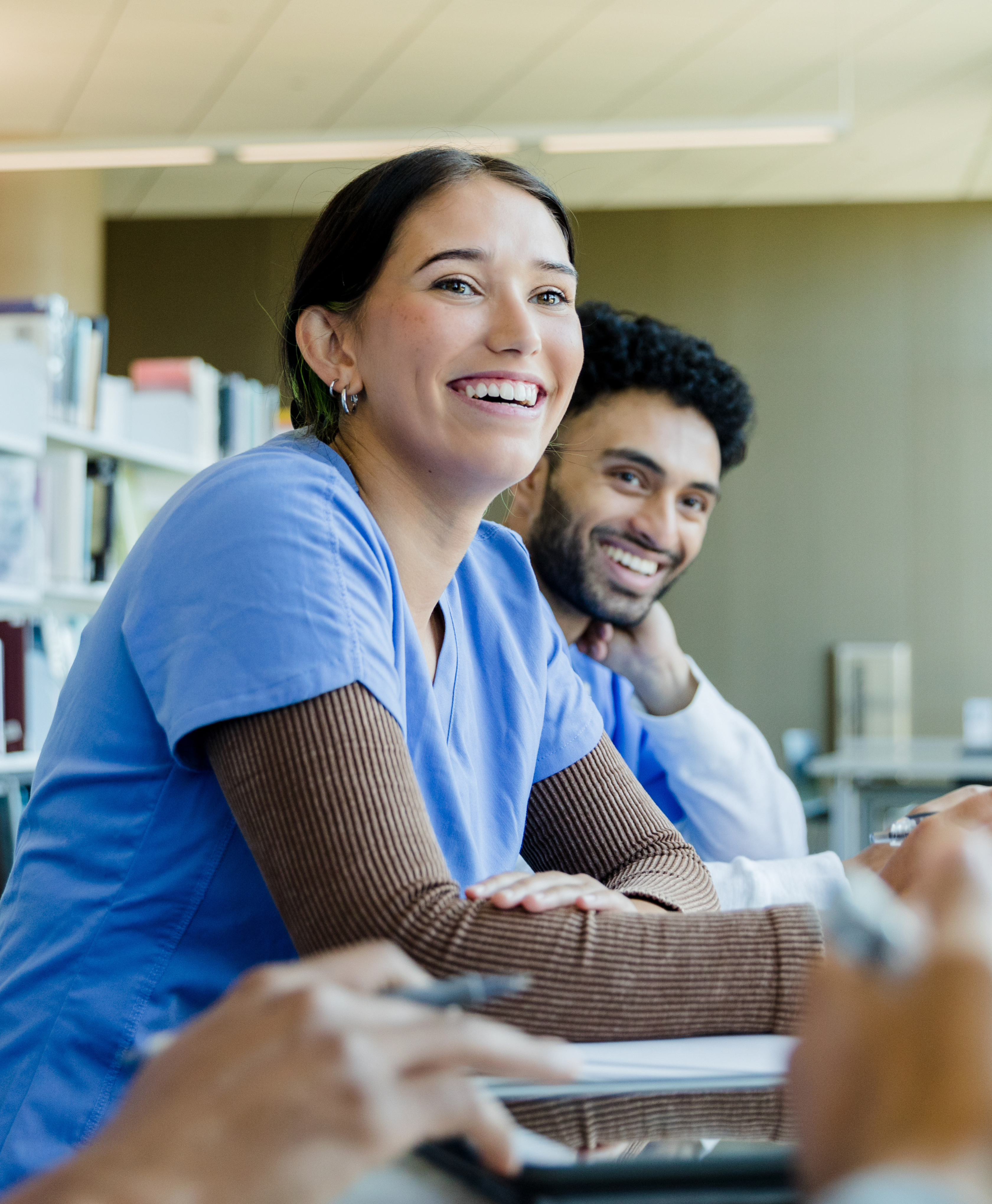 Two smiling healthcare workers in scrubs during a training session.